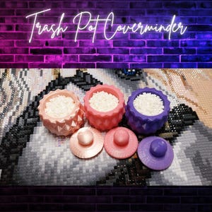 Puede incluir: Tres Trash Pot Coverminders coloridos en rosa, coral y morado, cada uno lleno de cuentas blancas. Las tapas a juego están al frente. El fondo es una pintura de diamantes con una pared de ladrillos y un letrero de neón que dice "Trash Pot Coverminder".