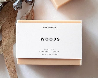 May include: A rectangular bar of soap with a white label that reads "YOUR BRAND CO. WOODS SOAP BAR HANDMADE | VEGAN NET WT: 150 g/5.6 oz."