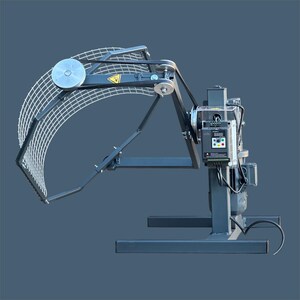 May include: A gray metal machine with a curved white net, pulleys, and a control panel. The machine has a black belt system and a warning triangle symbol. The base is rectangular, and the background is a solid blue-gray.