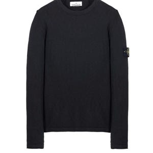 Peut inclure: Un pull noir à col rond et manches longues. Le pull présente une petite étiquette blanche au niveau de l'encolure et un écusson avec un logo sur la manche gauche. Le pull est en tissu tricoté.