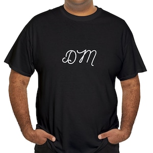 Könnte beinhalten: Ein schwarzes T-Shirt mit einem weißen, kursiv geschriebenen "DM" auf der Vorderseite.
