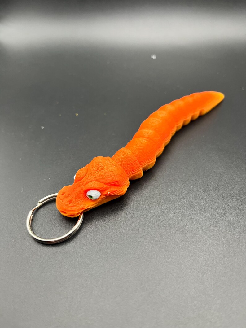 May include: Orange and yellow plastic keychain shaped like a worm with a silver key ring.
