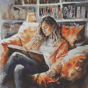 May include: A woman in a cozy orange sweater sits on a couch reading a book. She has long brown hair and is wearing blue jeans. The couch is covered in a soft, orange fabric and there are pillows behind her.
