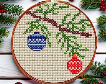 May include: A cross-stitch embroidery in a wooden hoop features a Christmas tree branch with two ornaments. One ornament is blue with white dots, and the other is red with white dots. The background is a light beige fabric.