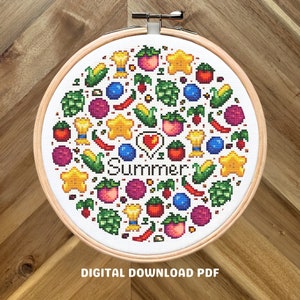 May include: A white cross-stitch pattern with a circle of colorful summer-themed icons, including stars, fruit, corn, and peppers. The text "I love Summer" is in the center of the circle.