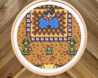May include: Cross stitch pattern of a video game scene with a character in a blue pool surrounded by hearts and enemies. The pattern is in a round wooden embroidery hoop.