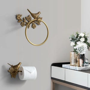 Puede incluir: Juego de toallero y portarrollos de metal dorado. Cada pieza presenta un p&aacute;jaro posado en una rama floral. El toallero es circular y el portarrollos est&aacute; dise&ntilde;ado para un rollo est&aacute;ndar.