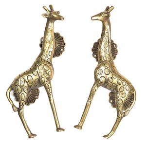 Könnte beinhalten: Zwei Messing-Giraffen-Skulpturen mit detaillierten Flecken und einer dekorativen Blumenbasis. Die Giraffen stehen aufrecht mit ausgestrecktem Hals. Die Skulpturen sind aus goldfarbenem Metall gefertigt.