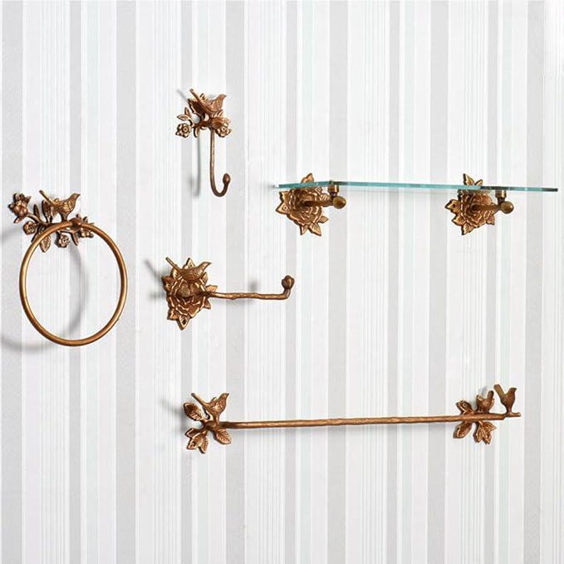 Puede incluir: Un conjunto de accesorios de ba&ntilde;o de color bronce, que incluye un anillo para toallas, un gancho, un portarrollos de papel higi&eacute;nico, una barra para toallas y una estanter&iacute;a de cristal. Cada pieza presenta un dise&ntilde;o de p&aacute;jaros y flores.