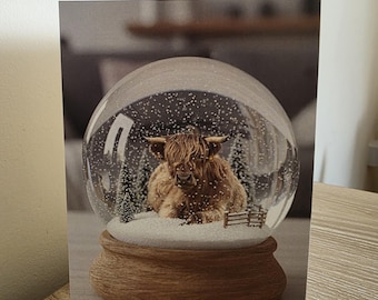 A Highland cow  in a snow globe  plain greetings card with  envelope