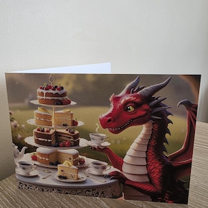 Puede incluir: Tarjeta de felicitación con un dragón rojo tomando el té. El dragón sostiene una taza de té, con un soporte para pasteles de varios niveles y tazas de té sobre una mesa. Los pasteles están decorados con bayas y glaseado.