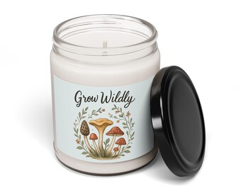 May include: A white candle in a glass jar with a black lid. The candle has a label with the text "Grow Wildly" and a mushroom illustration in shades of brown, orange, and red. The lid is off to the side.