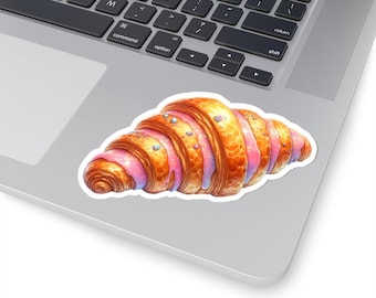 May include: A croissant with pink icing and colourful sprinkles. The croissant is on a white background.