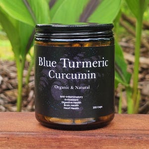 May include: A glass jar filled with yellow capsules labelled "Blue Turmeric Curcumin Organic & Natural". The label also lists benefits including anti-inflammatory, antioxidant, digestive health, brain health, and heart health. The jar contains 200 capsules.
