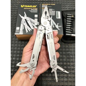 以下が含まれることがあります： ペンチ、ナイフ、その他のツールを備えたシルバーのマルチツールが展開されて表示されています。ツールは手で持たれており、背景には箱と黒いキャリングケースがあります。箱には「TRAVELER MECHANICAL PLIERS MULTI-TOOL」と書かれています。