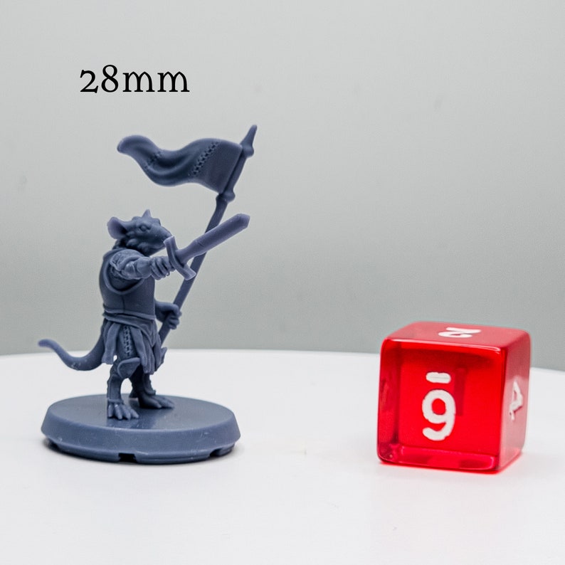 May include: A gray plastic miniature of a rat-like creature wearing armor and holding a sword and a flag. The miniature is standing on a round base. A red 9-sided die is in the background.