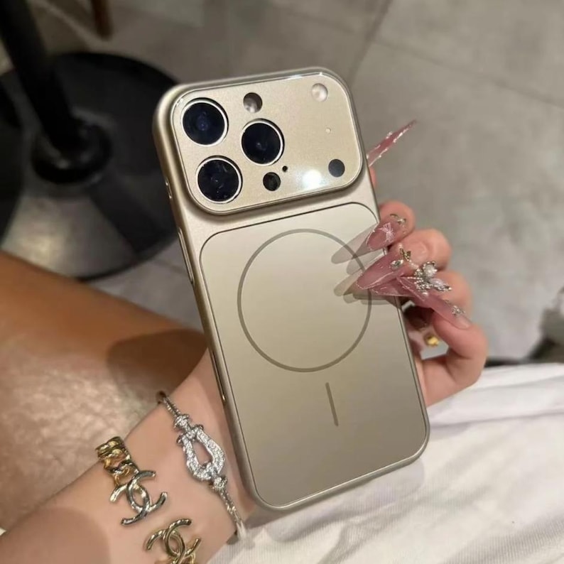 May include: A gold-colored phone case with a camera module and a circular design on the back. The case has a sleek, modern design and appears to be made of a durable material. The case is designed to fit a smartphone.