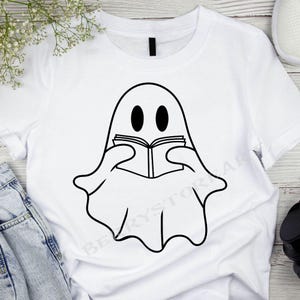 May include: White t-shirt with a black and white illustration of a ghost reading a book.