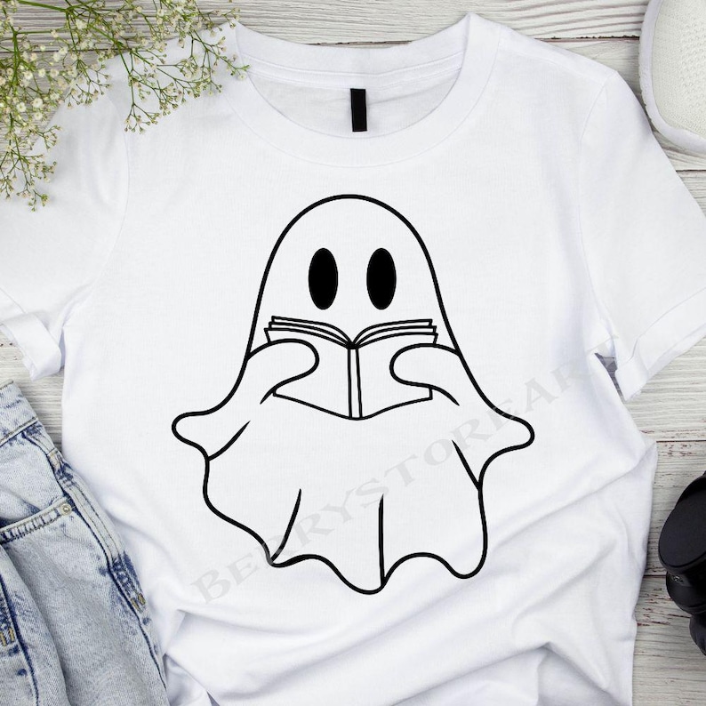 May include: White t-shirt with a black and white illustration of a ghost reading a book.