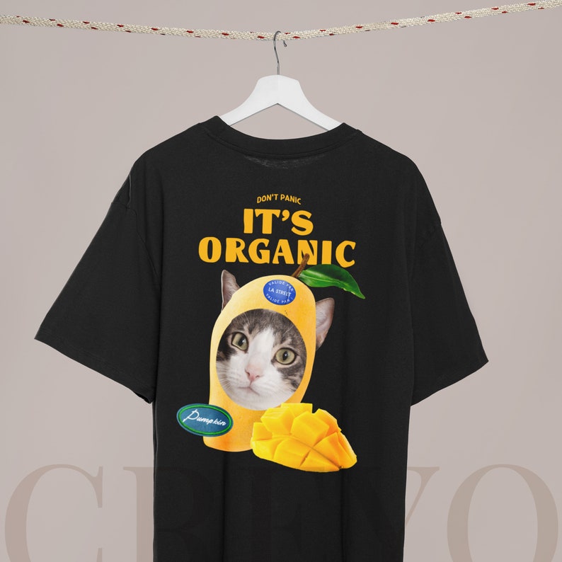 May include: Black t-shirt with a graphic of a cat wearing a mango. The text "Don't Panic It's Organic" is printed on the shirt.