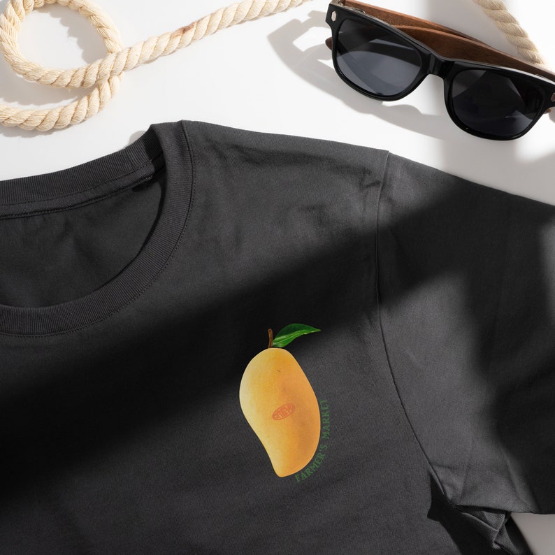 May include: Black t-shirt with a yellow mango and green leaves graphic. The text "Farmer's Market" is printed below the mango.