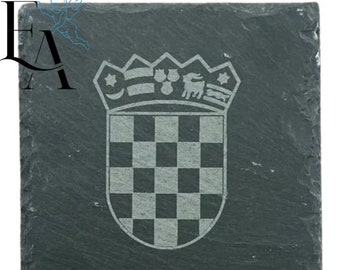 May include: A black slate coaster with a white engraved design of the Croatian coat of arms. The coat of arms features a checkered shield with a crown above it.