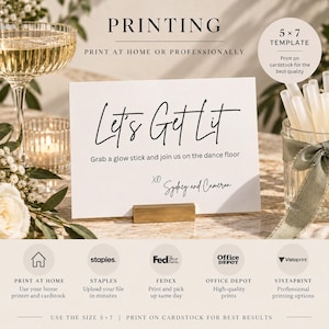 May include: A white 5x7 inch rectangular cardstock sign with black text reading Let's Get Lit, Grab a glow stick and join us on the dance floor, and XO Sydney and Cameron. The sign is held by a gold metal stand on a surface with a glass and glow sticks.