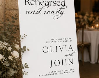 May include: A white rectangular sign on a wooden easel featuring black text that reads Rehearsed and ready, Welcome to the rehearsal dinner of Olivia and John, Saturday 11th June, 123 Anywhere St., Any City, with a clean and modern layout.