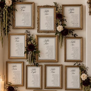 Peut inclure: Un plan de table de mariage composé de dix cadres dorés numérotés de un à dix, avec le texte Our Favorite People FIND YOUR SEAT et une plaque indiquant OLIVIA + JONATHAN 06.14.2026, le tout décoré de compositions florales rouge foncé et blanches.