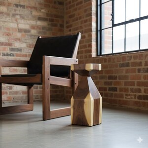 May include: A wooden side table with a geometric design, featuring alternating sections of light and dark wood. The table is approximately 18 inches tall and stands on a concrete floor. A wooden chair with a black seat is in the background.