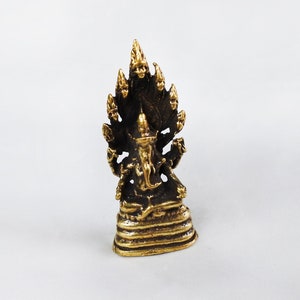 May include: A small, detailed brass statue of a deity with multiple arms and a multi-headed serpent headdress. The statue is golden-brown in color and stands on a tiered base. The background is plain white.