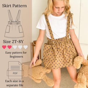 May include: A tan skirt with black polka dots, an elasticated waistband, two patch pockets, and attached suspender straps. The image includes text: Skirt Pattern, Size 2T-8Y, Easy pattern for Beginners, and a PDF icon indicating each size is in a separate file.