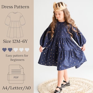 May include: A navy blue dress with long puff sleeves and a tiered skirt, featuring a gold heart pattern. The image includes text: Dress Pattern, Size 12M-6Y, Easy pattern for Beginners, PDF, A4/Letter/A0, and a line drawing of the dress.