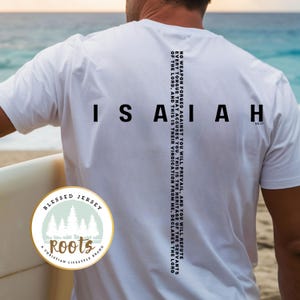 May include: White t-shirt with black text that reads "ISAIAH 54:17" and a smaller text that reads "NO WEAPON FORGED AGAINST YOU WILL PREVAIL, AND YOU WILL REFUTE EVERY TONGUE THAT ACCUSES YOU. THIS IS THE HERITAGE OF THE SERVANTS OF THE LORD, AND THIS IS THEIR VINDICATION FROM ME, DECLARES THE LORD". The shirt also has a small logo that reads "BLESSED JERSEY Roots A CHRISTIAN LIFESTYLE BRAND".