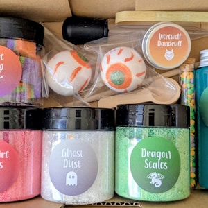 May include: A Halloween gift set containing jars of novelty items like "Ogre Poop," "Vampire Ashes," "Ghost Dust," and "Dragon Scales." Also includes "Witch Tears" potion, eye-shaped bath bombs, and a small wooden spoon, all in a box.