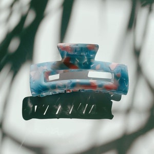 May include: A blue and pink patterned plastic hair claw clip.