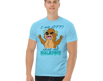 Op de afbeelding: Een lichtblauw t-shirt met een cartoon-otter die een bruine vachtjas draagt. De otter schreeuwt "Ik ben OTT! Hoor me piepen!" in blauw en groen lettertype.
