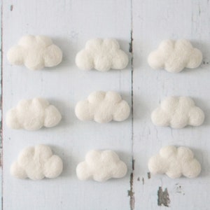 May include: Nine white felt clouds arranged in three rows of three. The clouds are all the same size and shape.
