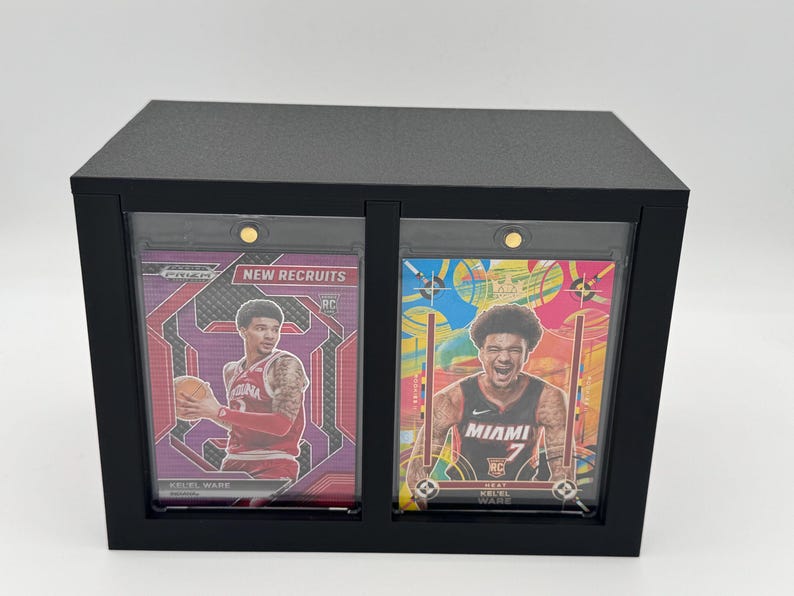 Puede incluir: Una vitrina rectangular negra que contiene dos tarjetas deportivas en soportes magn&eacute;ticos protectores. La tarjeta izquierda muestra a un jugador con camiseta roja y el texto New Recruits, la derecha a un jugador con camiseta de Miami.