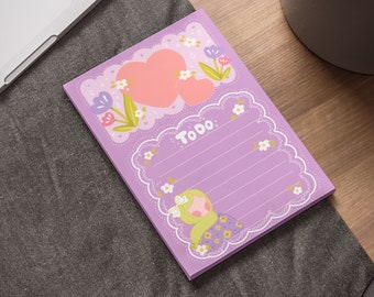 May include: Purple notepad with a floral design and a heart. The notepad has a section for writing a to-do list with the word "Todo" written on it.