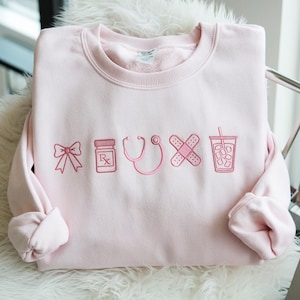 Embroidered Nurse Icon Sweatshirt, Healthcare Shirt, CNA Sweatshirt, Medical Assistant, Nursing Grad Gift, Coquette Nursing Sweatshirt