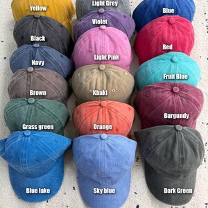 Op de afbeelding: Een verzameling baseballpetten in diverse kleuren, waaronder geel, lichtgrijs, blauw, violet, zwart, rood, lichtroze, marineblauw, fruitblauw, bruin, kaki, bordeaux, grasgroen, oranje, blauw meer, hemelsblauw en donkergroen. Elke pet heeft een gebogen klep.