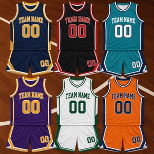 May include: Six sets of basketball uniforms, each consisting of a sleeveless jersey and matching shorts. Each jersey features the text TEAM NAME and the number 00 on the front. The sets come in navy, black, teal, purple, white, and orange colours.