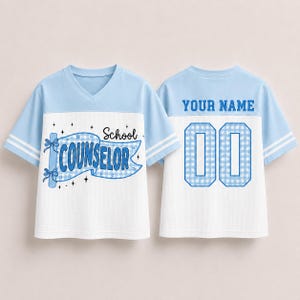 May include: A light blue and white V-neck jersey with short sleeves and double white stripes. The front features a blue gingham banner with the text School COUNSELOR and star accents. The back displays the text YOUR NAME above the number 00.