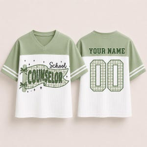 May include: A sage green and white V-neck jersey with short sleeves featuring two white stripes. The front displays a banner graphic with the text School COUNSELOR. The back shows the text YOUR NAME above the double-digit number 00 in a gingham pattern.