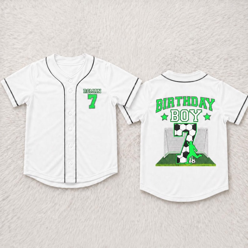 May include: White baseball jersey with black trim and button closure. The front features the name "ROMAN" and the number "7" in green. The back displays "BIRTHDAY BOY" and a soccer-themed graphic with the number 7.