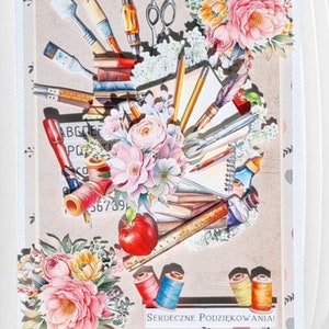 May include: A decorative card featuring an artistic arrangement of art supplies and floral elements. The design includes paintbrushes, pencils, scissors, spools of thread, and an apple, all set against a neutral background with the text "SERDECZNE PODZIĘKOWANIA!"