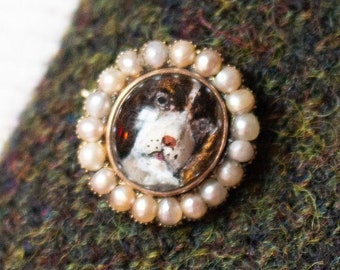 May include: A gold brooch with a pearl border and a miniature portrait of a dog inside.