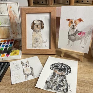Puede incluir: Retratos de perros en acuarela, incluyendo una imagen enmarcada de un perro esponjoso de color claro. Otros retratos presentan un Jack Russell Terrier, un Bulldog Franc&eacute;s y un Schnauzer. Una paleta de acuarela y materiales de arte son visibles.