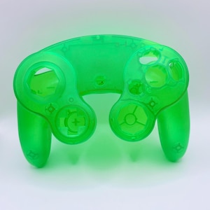 May include: A translucent green GameCube controller shell. The shell is made of plastic and has all of the buttons and ports for a standard GameCube controller.